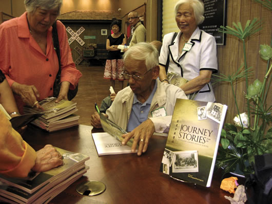 Paul Wong signs a copy of Journey Stories from the Chinese Mission School  at the Martin & Sue King Railroad Heritage Museum.
